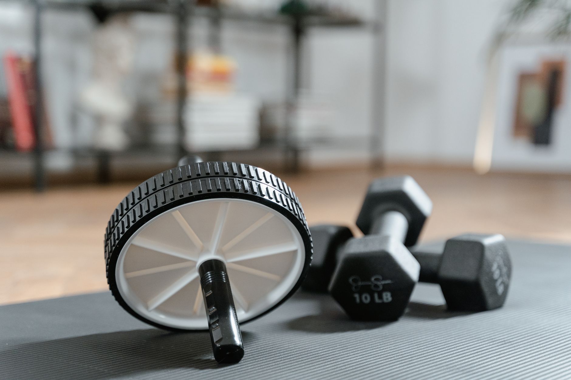 Ab-Roller und Kurzhanteln auf einer Trainingsmatte für Core-Übungen